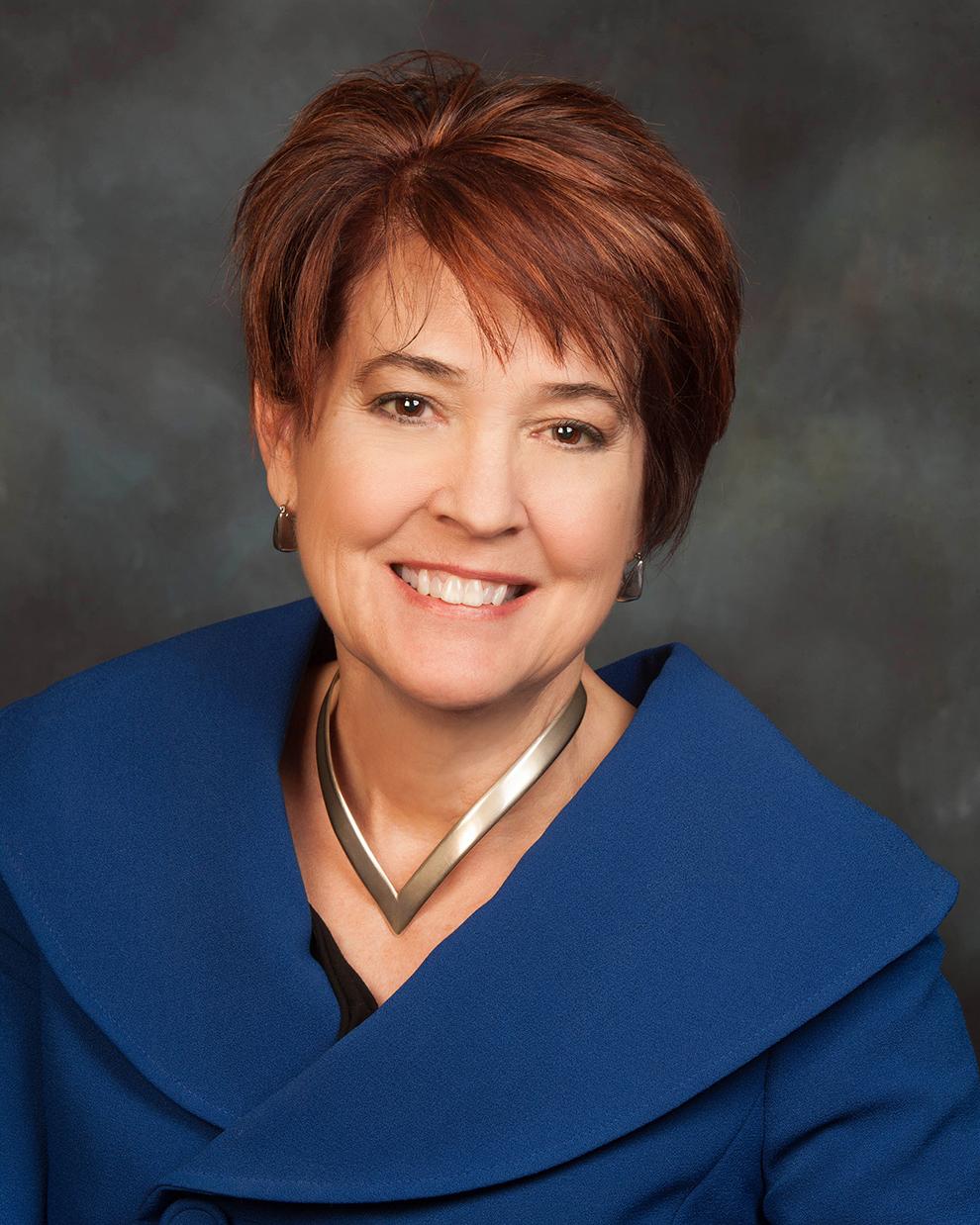 A portrait of Bonnie Suderman, a smiling woman with short brown hair, wearing a blue jacket.